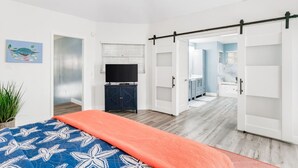 Une chambre moderne équipée d’un lit, d’une télévision et d’une porte coulissante donnant accès à une salle de bain.