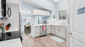 Une cuisine moderne avec des meubles blancs, un four encastré et un coin repas comprenant une table et des chaises.