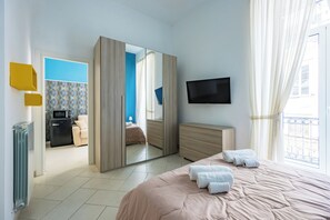 Une chambre d’hôtel moderne avec un grand lit, une télévision, un miroir et une vue sur la ville.
