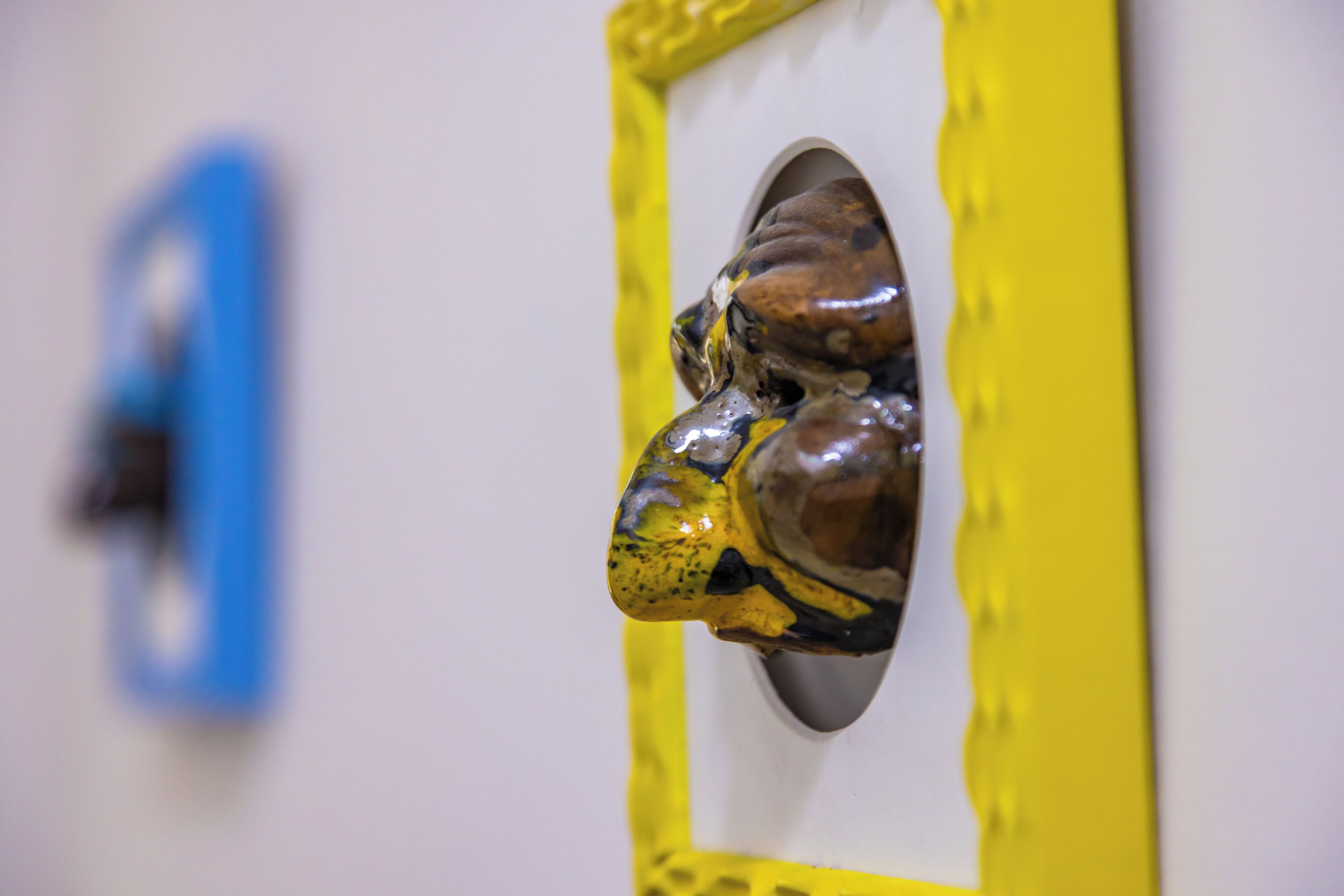 Primer plano de un objeto con marco amarillo y superficie texturizada, posiblemente una escultura o adorno.