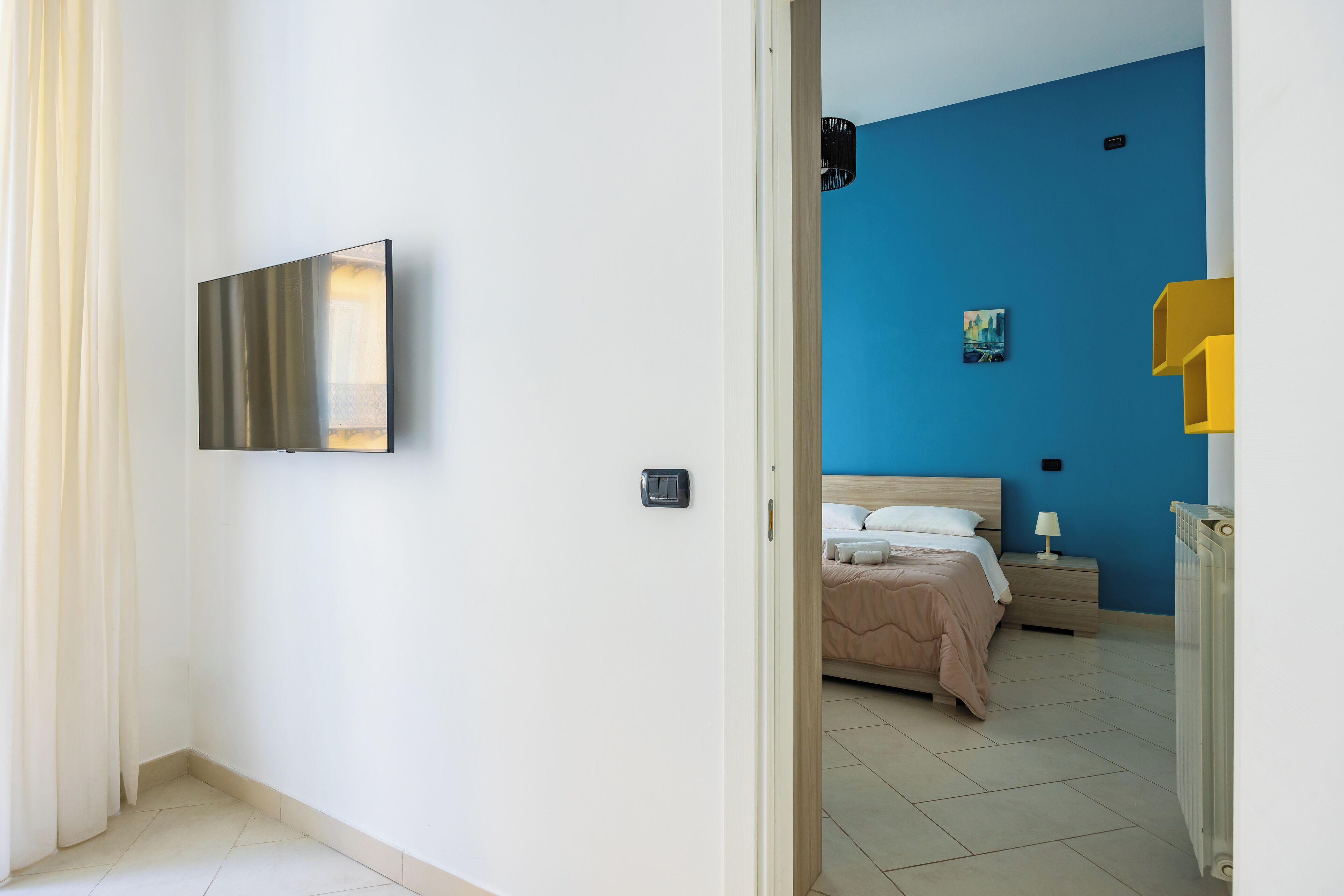 Un dormitorio con cama, mesita de noche, lámpara y un cuadro en la pared.