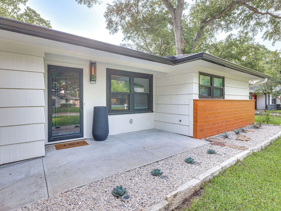 A modern house with a front porch, a large window, and a door.