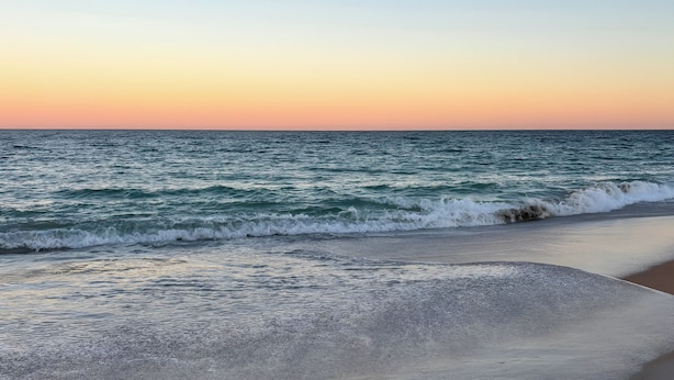 A beach with waves gently lapping onto the shore under a clear sky. - Home Near Flagler Beach, Daytona, Parks & More! (Palm Coast)
