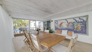 A spacious dining area with a wooden table and chairs, a large mosaic artwork on the wall, and a view of the outdoors. - Lanai, Pool & Patios: Waterfront Home in Tavernier (Tavernier)