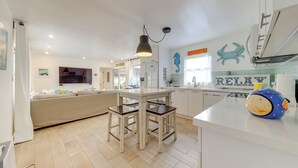 A modern kitchen with a dining area, white cabinetry, a large island, and a blue decorative item on the counter. - Lanai, Pool & Patios: Waterfront Home in Tavernier (Tavernier)