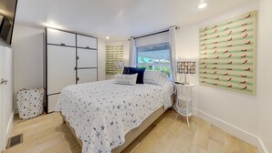 A bedroom with a bed, a wardrobe, a window with curtains, and a wall-mounted artwork. - Lanai, Pool & Patios: Waterfront Home in Tavernier (Tavernier)