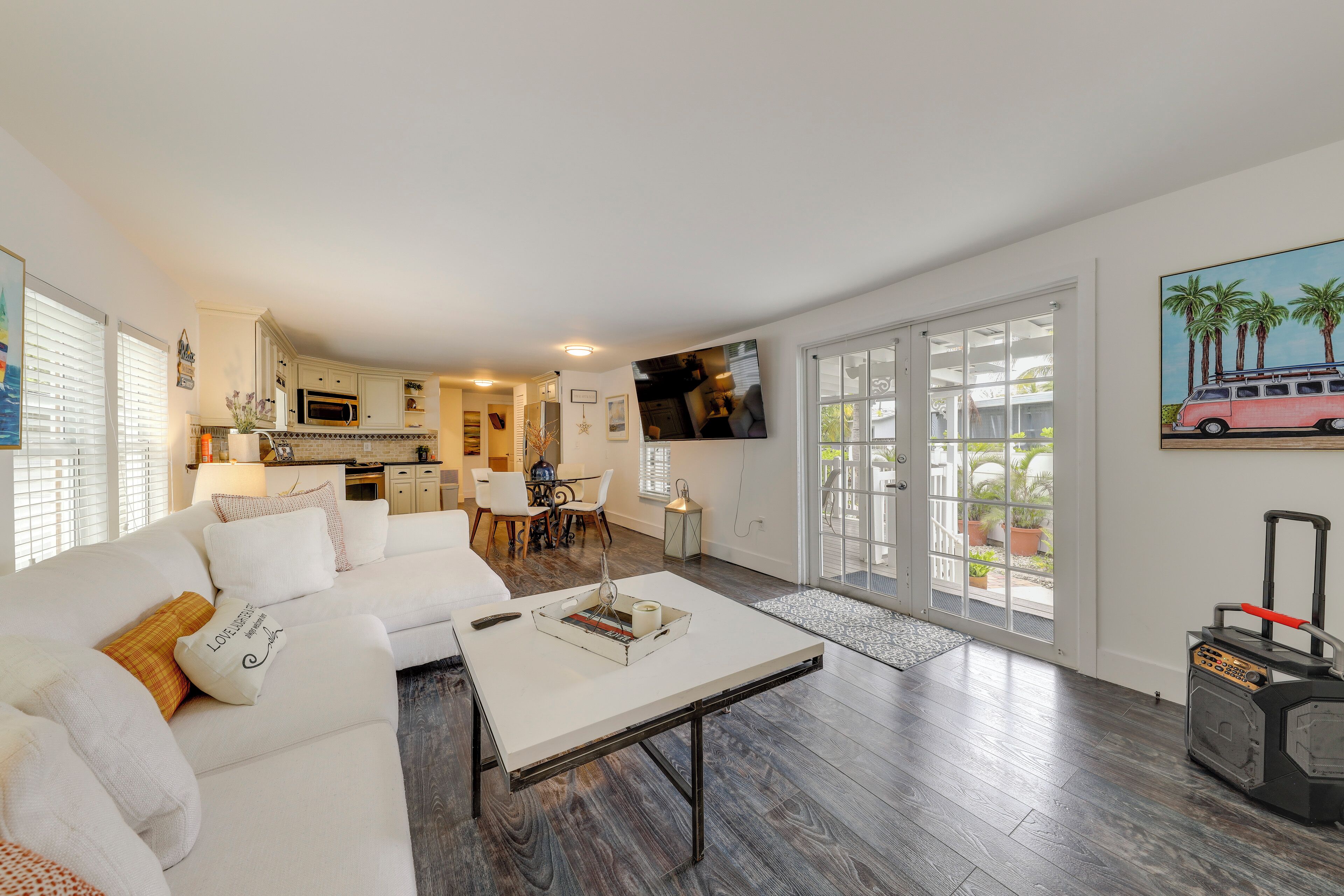 A modern living room with a white sofa, a coffee table, and a kitchen in the background.