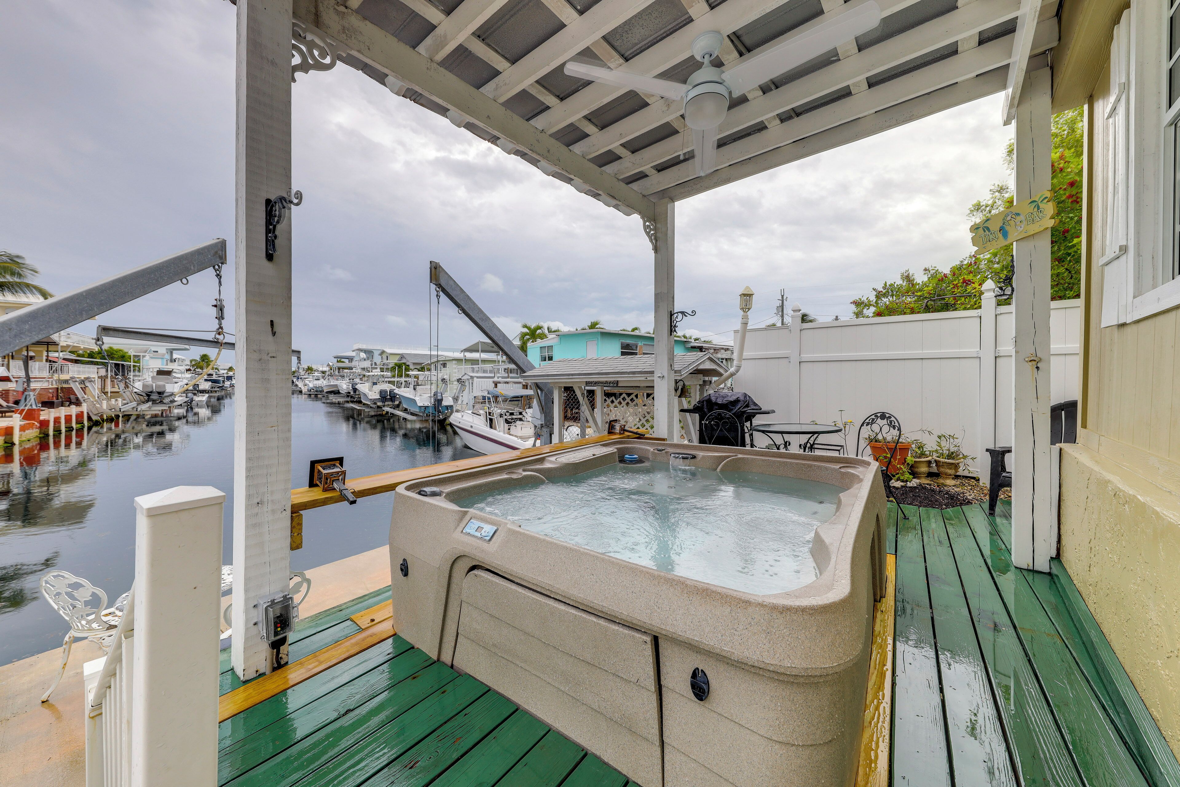 A hot tub on a wooden deck with a view of a marina and boats.