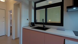 A modern kitchen with a black sink, a window above the counter, and a visible dishwasher.