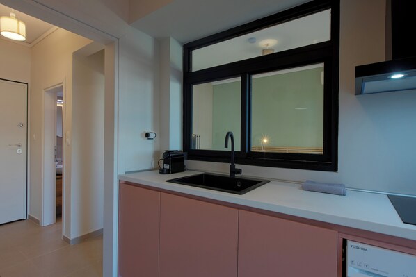 Een moderne keuken met een zwarte spoelbak, een raam boven de aanrecht en een zichtbare vaatwasser.