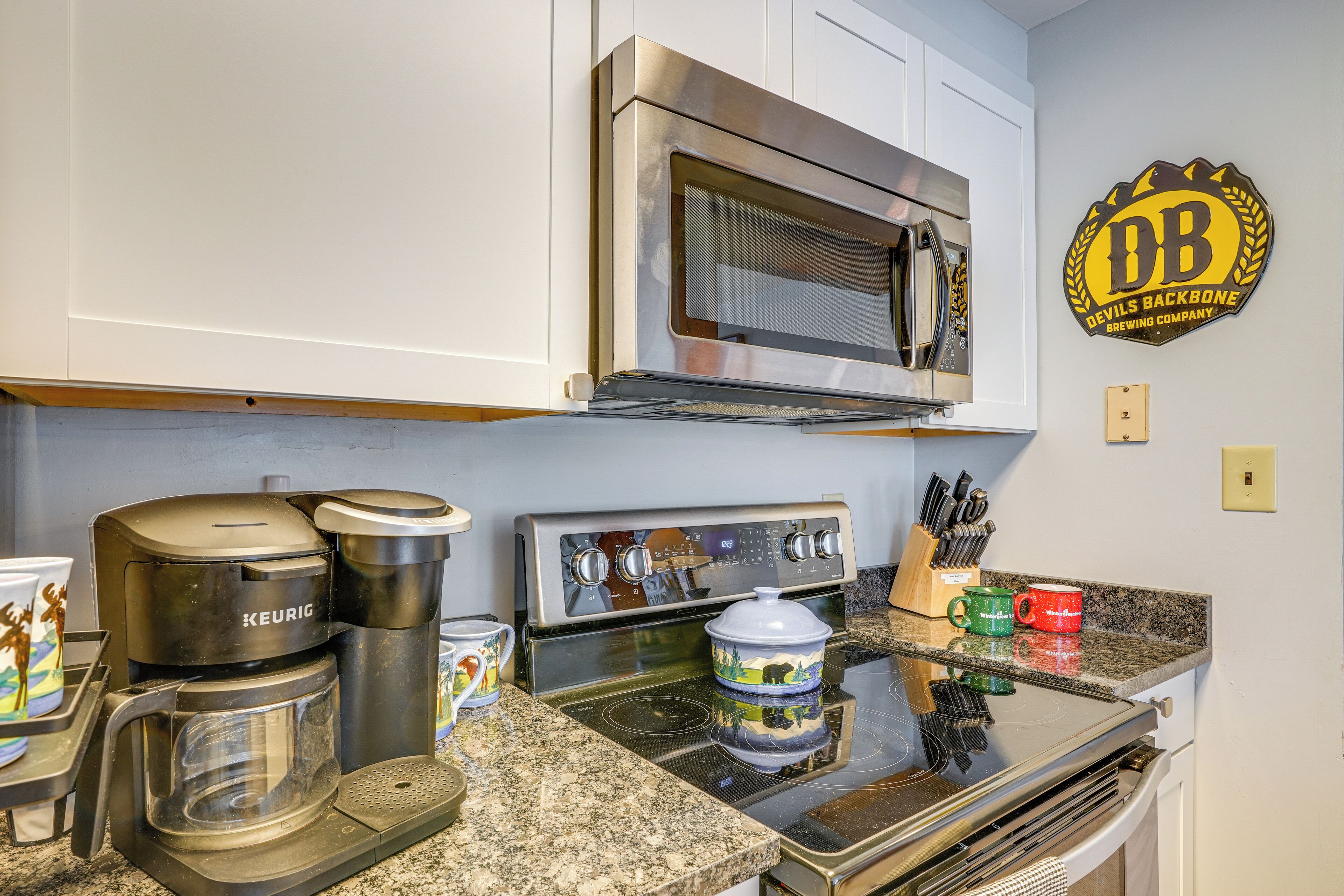 A kitchen with a Keurig coffee maker, a microwave, a stove, and a pot on the counter.