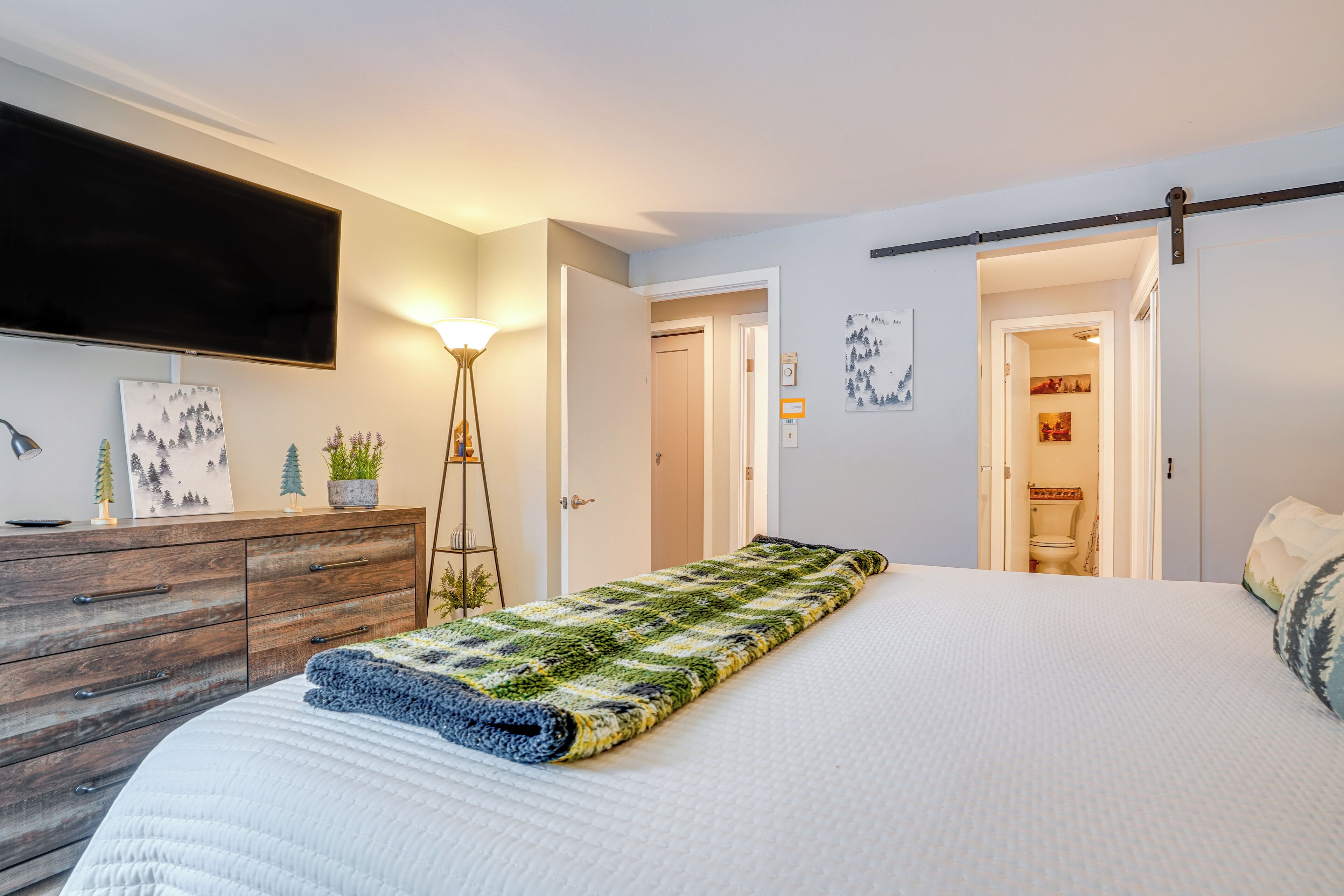 Ein Schlafzimmer mit Bett, Schminktisch, Fernseher und einer Tür zu einem Badezimmer.