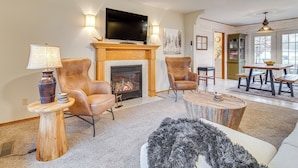 A living room with a fireplace, leather armchairs, a round coffee table, and a television mounted above the fireplace. - < 1 Mi to Bull Shoals Lake: 'the Blue Quill' (Bull Shoals)