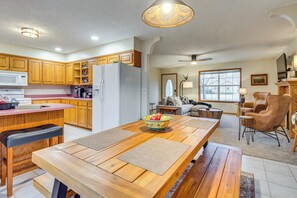 A spacious kitchen with wooden cabinets, a large island with a bowl of fruit, and a dining area with a bench. - < 1 Mi to Bull Shoals Lake: 'the Blue Quill' (Bull Shoals)