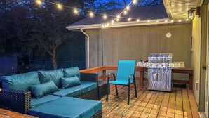 Een terras buiten met een blauwe bank, een blauwe stoel en een barbecue.