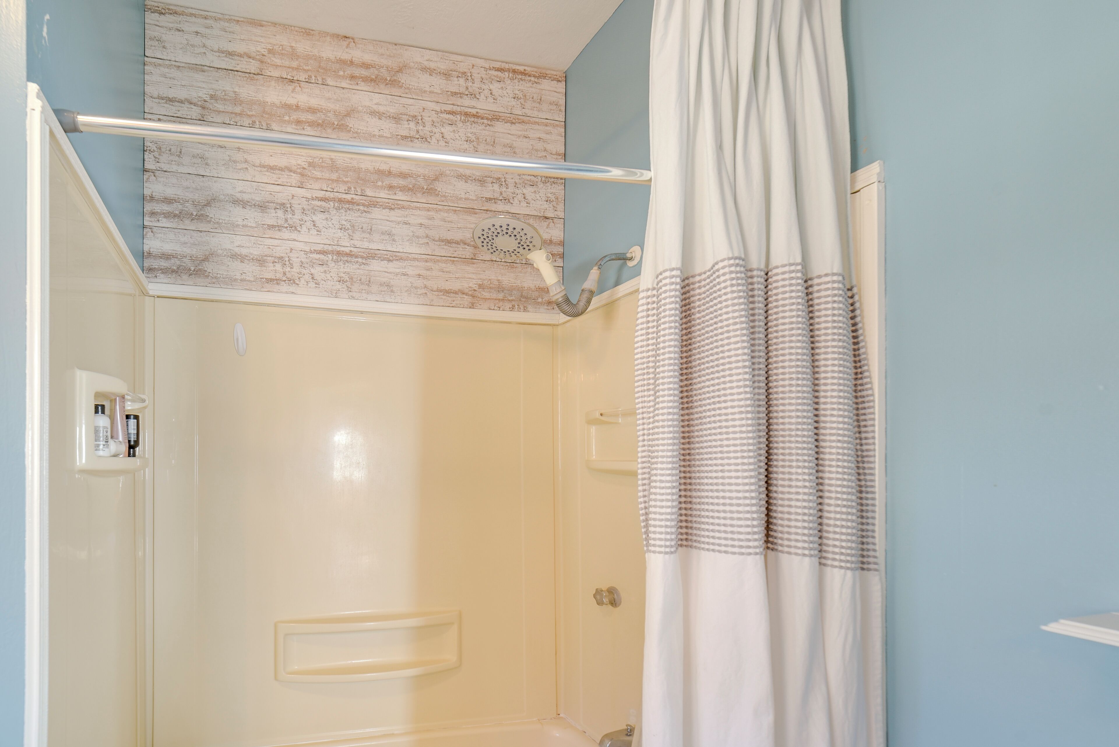 A shower area with a glass door, a towel rack, and a showerhead.