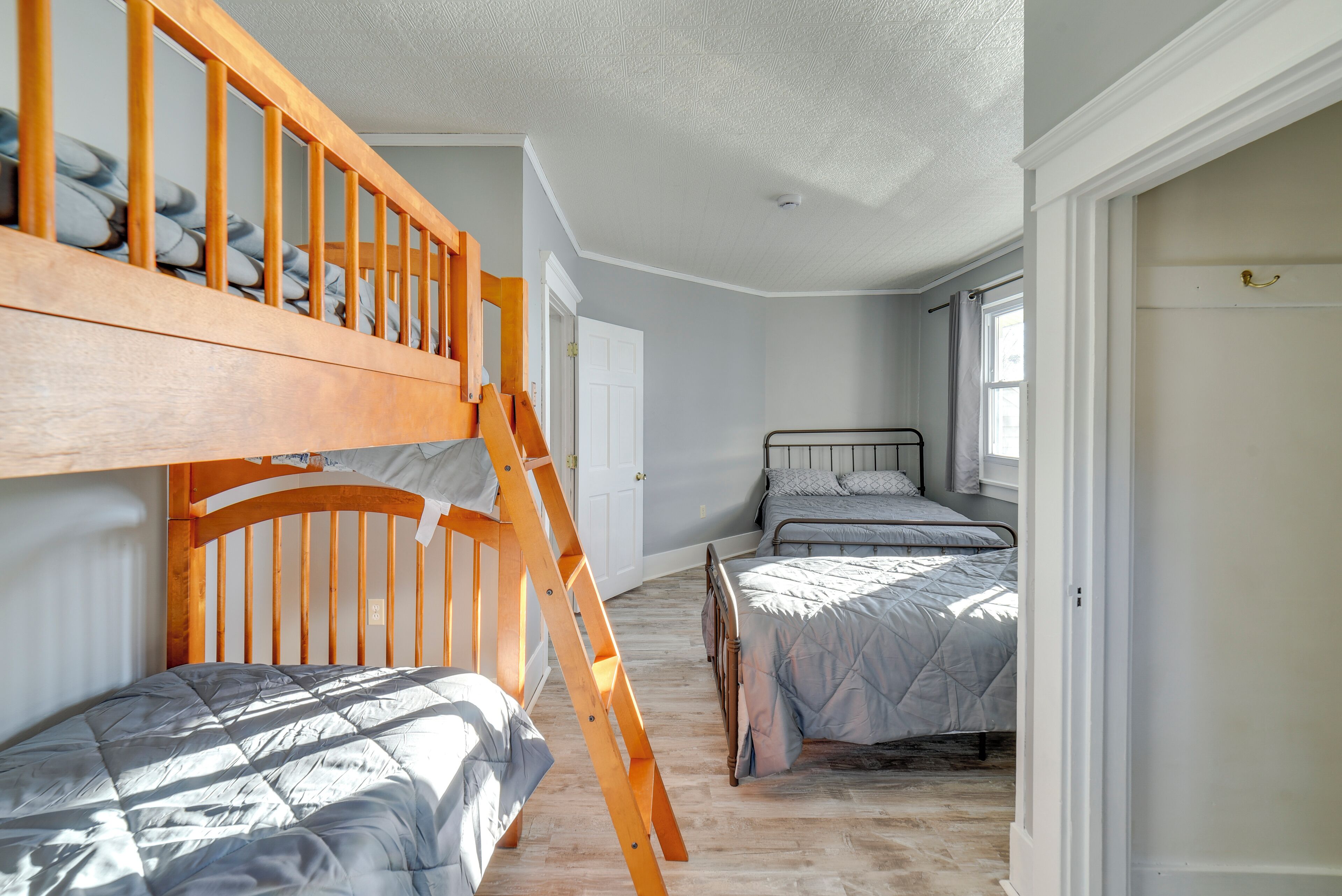 A bedroom with bunk beds, a wooden ladder, and a window.