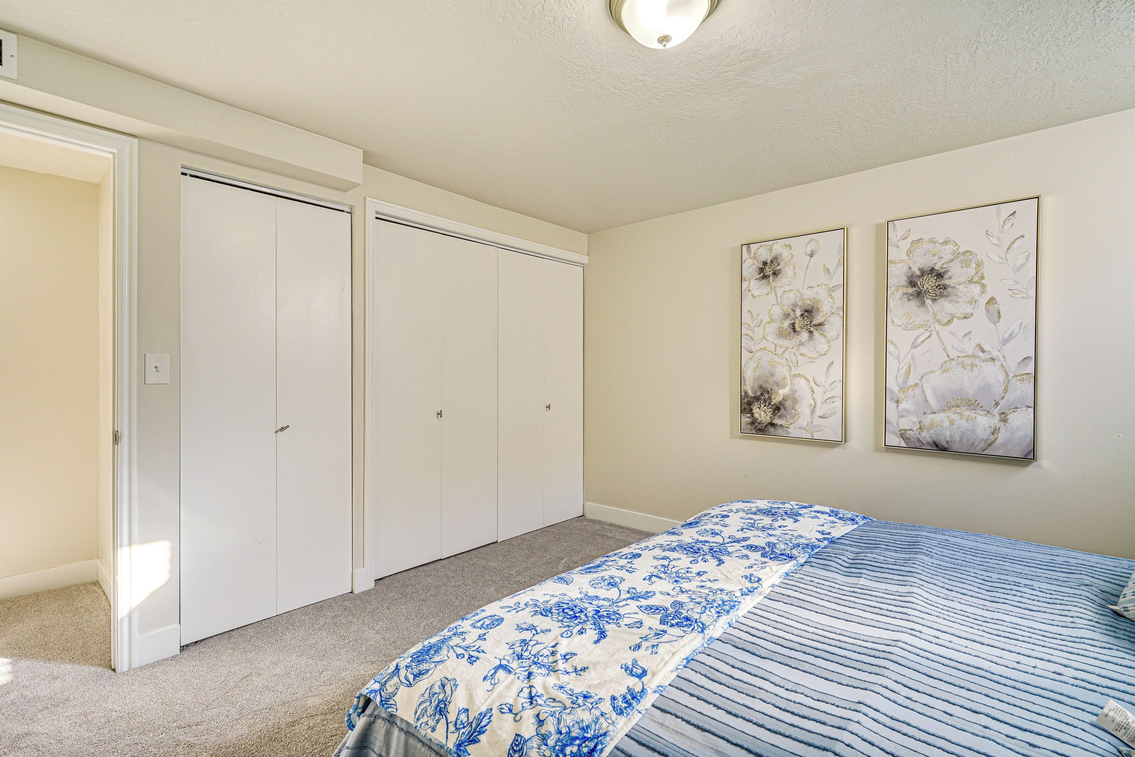 Un dormitorio con cama, armario y dos cuadros florales colgados en la pared.