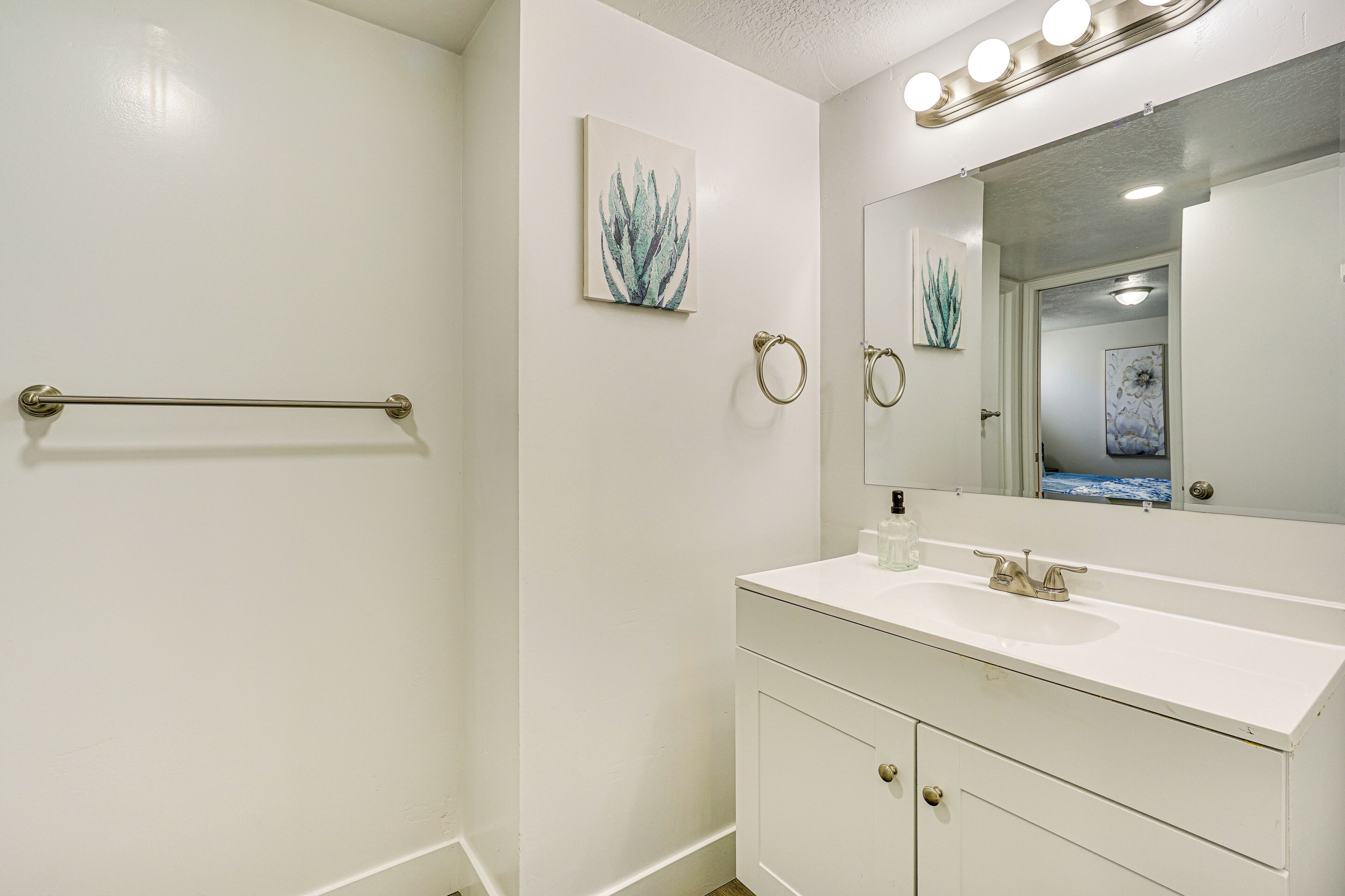 A bathroom with a white sink, vanity, and a towel rack.
