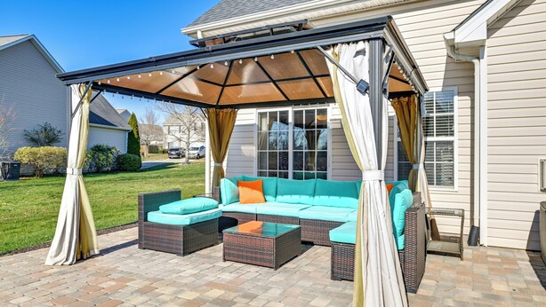 An outdoor patio with a covered seating area, a wicker sofa, and a glass-top table. - 6 Mi to Charlotte Motor Speedway: Home w/ Fire Pit (Concord)