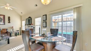 A spacious living area with a glass-top dining table surrounded by chairs, a sofa, and a television. - 6 Mi to Charlotte Motor Speedway: Home w/ Fire Pit (Concord)