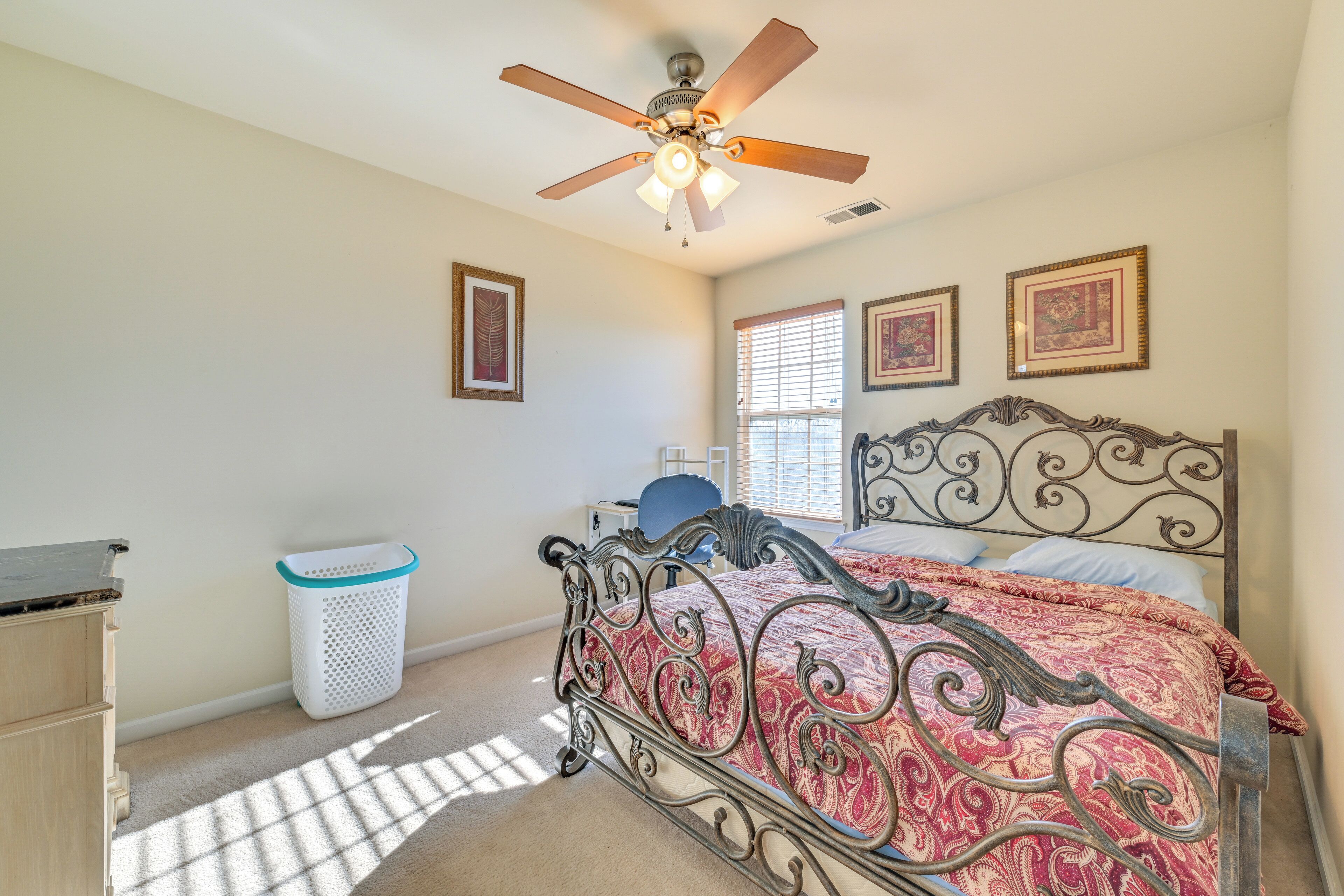A bedroom with a bed, a ceiling fan, a window, and a wall-mounted picture frame.