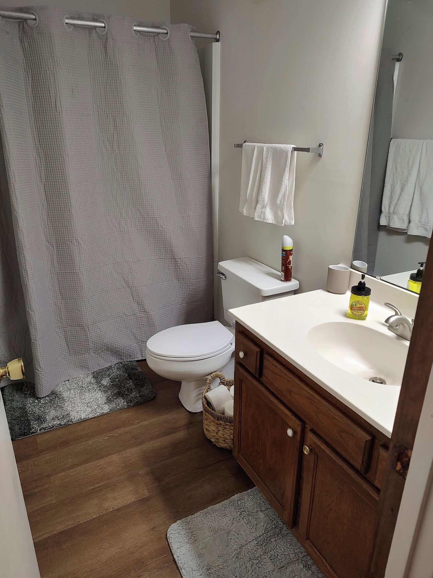 Une salle de bain avec un rideau de douche, des toilettes, un lavabo et un meuble en bois.