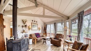 A cozy cabin interior with a fireplace, wooden furniture, and large windows. - BW-7  Mountain Treehouse Authentic Roundhouse (Beech Mountain)