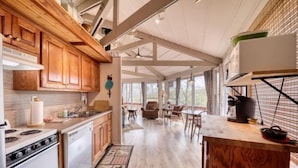A spacious kitchen with wooden cabinets, a stove, and a dining area with chairs and a table. - BW-7  Mountain Treehouse Authentic Roundhouse (Beech Mountain)