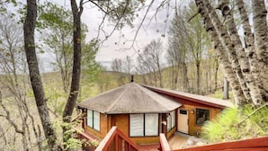 A wooden cabin with a sloped roof, surrounded by trees and a wooden deck. - BW-7  Mountain Treehouse Authentic Roundhouse (Beech Mountain)