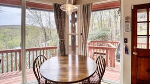 A wooden dining table with chairs, a hanging light fixture, and a view of trees through large windows. - BW-7  Mountain Treehouse Authentic Roundhouse (Beech Mountain)