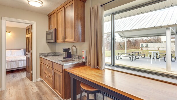 Una cocina con armarios de madera, un microondas y un amplio ventanal con vista a un patio exterior.
