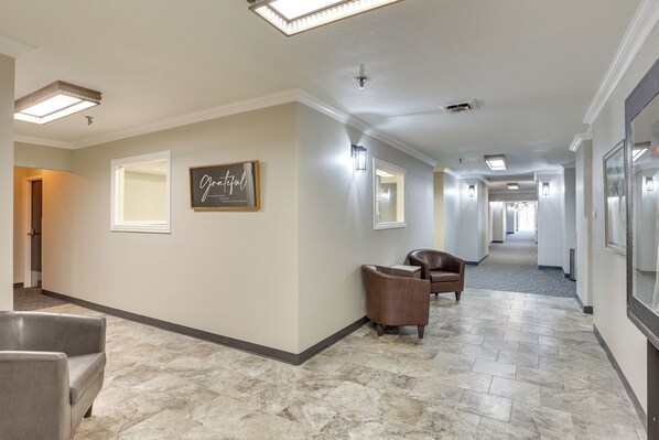 A hotel corridor with a marble floor, leather chairs, and framed artwork on the walls. - Walk to Oakland City University: Modern Apartment! (Oakland City)