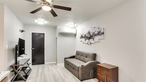 A room with a ceiling fan, a gray sofa, a wooden cabinet, and a wall-mounted air conditioner. - Half-mi to Oakland City Golf Club: Sleek Apartment (Oakland City)