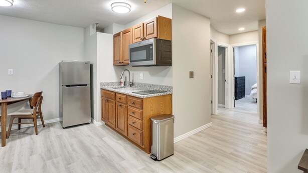 A kitchen with wooden cabinets, a stainless steel refrigerator, a microwave, and a sink. - Half-mi to Oakland City Golf Club: Sleek Apartment (Oakland City)