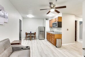 A modern kitchen with wooden cabinets, a stainless steel refrigerator, and a microwave. - Half-mi to Oakland City Golf Club: Sleek Apartment (Oakland City)