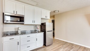 A kitchen with white cabinets, a stainless steel microwave, a refrigerator, and a granite countertop. - < 1 Mi to Oakland City University: Cozy Apartment (Oakland City)