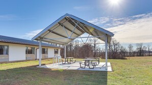 A covered outdoor area with picnic tables and a building in the background. - Walk to Ocu, Golf: Updated Oakland City Studio! (Oakland City)