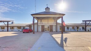 A building with a covered entrance, a red car parked in front, and two American flags. - Quiet Oakland City Studio: Walk Downtown! (Oakland City)