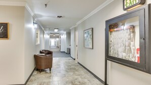 A hotel hallway with a brown leather chair, a framed picture on the wall, and an exit sign. - Quiet Oakland City Studio: Walk Downtown! (Oakland City)