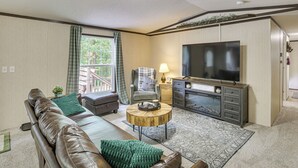 Ein Wohnzimmer mit Ledersofa, Fernseher, Couchtisch und Kamin.