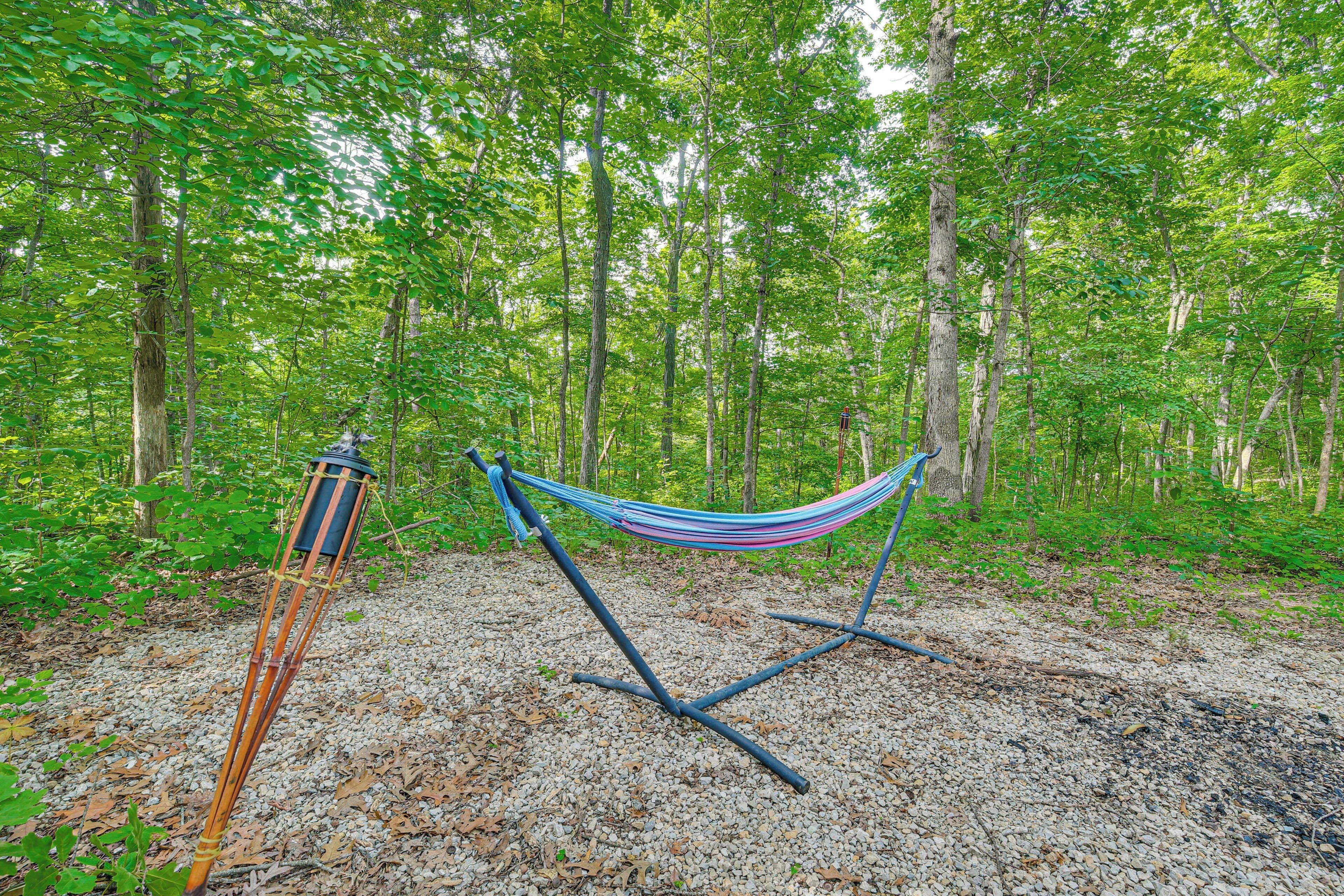A hammock set up on a gravel path in a forested area.