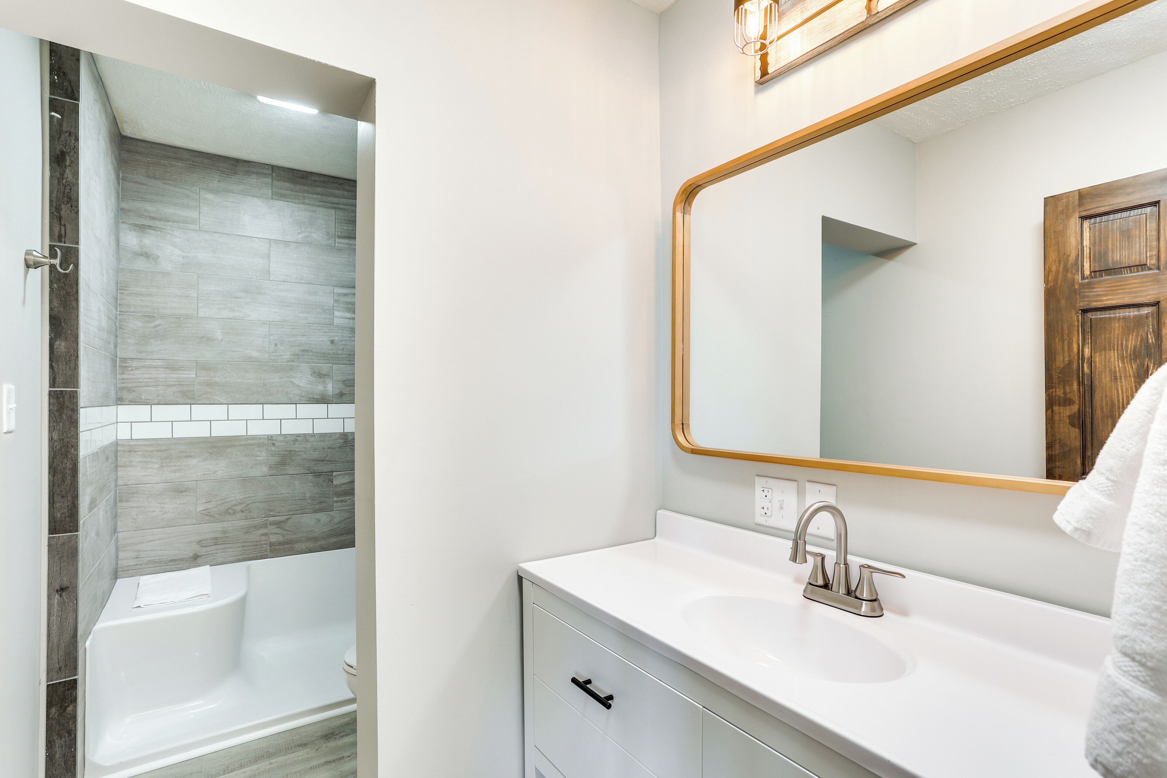 A modern bathroom with a bathtub, a sink, and a large mirror.