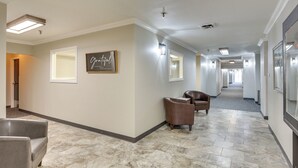A hotel corridor with a marble floor, leather chairs, and framed artwork on the walls. - Golf, Shop, Tour & More: Oakland City Apartment (Oakland City)
