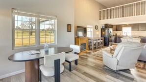 A spacious living area with a dining table, a comfortable sofa, and a view of the outdoors through large windows. - Golf Course Views: Oakland City Retreat (Oakland City)