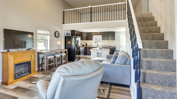 A spacious living area with a fireplace, a dining area, a kitchen, and a staircase leading to an upper level. - Golf Course Views: Oakland City Retreat (Oakland City)