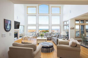 Un salon spacieux avec de grandes fenêtres, une cheminée et une vue sur la mer.