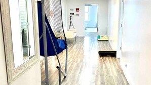 A hallway with wooden flooring, a blue chair, and a camera on a tripod. - Downtown condo Cozy 2-bedroom with plenty of space. (Owensboro)