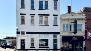 A two-story building with a white facade and black trim. There is a storefront with a sign that reads "Callas." - Downtown condo Cozy 2-bedroom with plenty of space. (Owensboro)