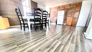 A dining area with a wooden floor, a white table, and striped chairs. - Downtown condo Cozy 2-bedroom with plenty of space. (Owensboro)
